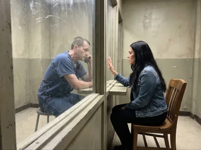 Prisoner and Visitor Communicating Through Glass Partition