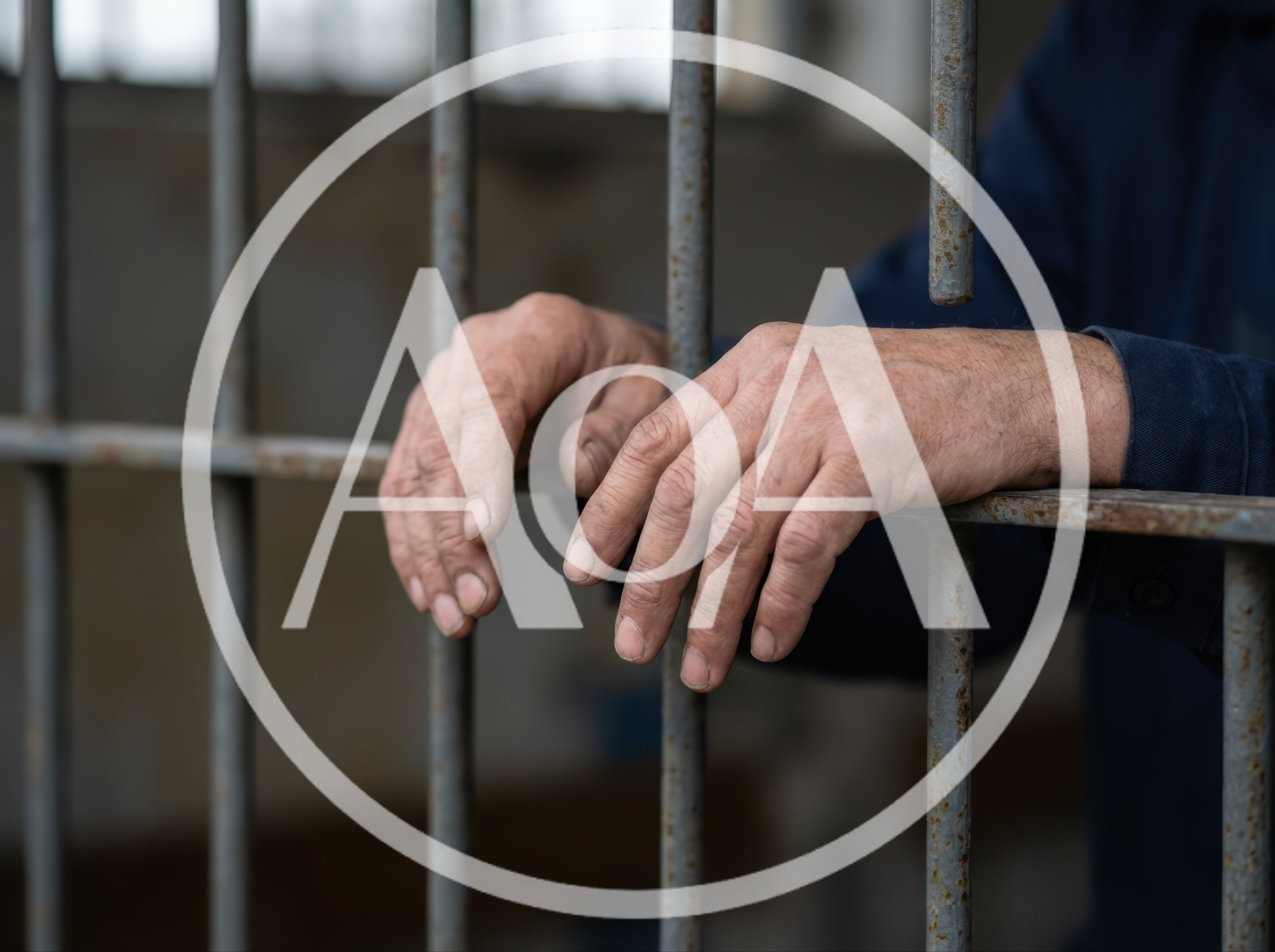 Close Up Of Prisoner Hands Gripping Metal Jail Bars