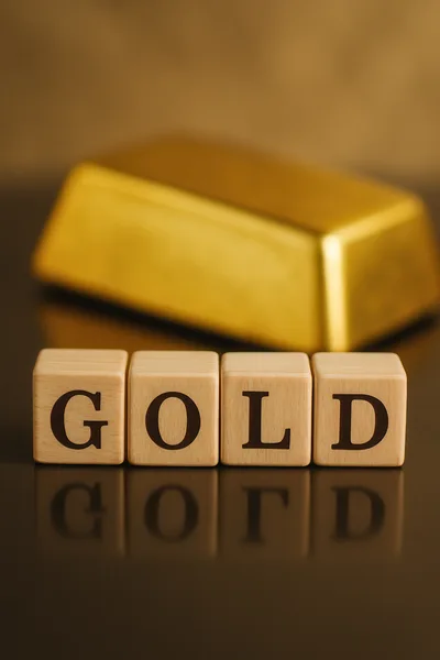 Gold Bar Behind Wooden Blocks Spelling Gold