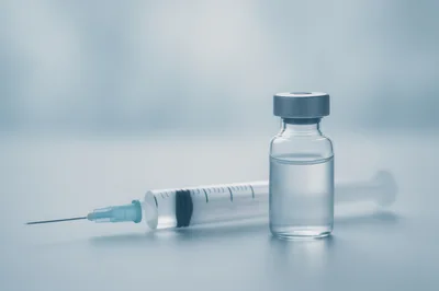 Medical Syringe And Vaccine Vial On Clinical Surface