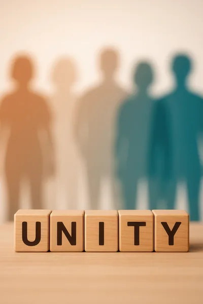 Wooden Blocks Spelling Unity With Blurred Human Silhouettes
