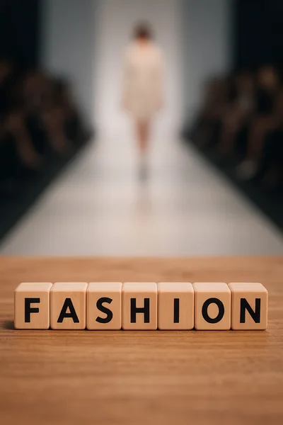 Wooden Blocks Spelling Fashion on a Runway Background