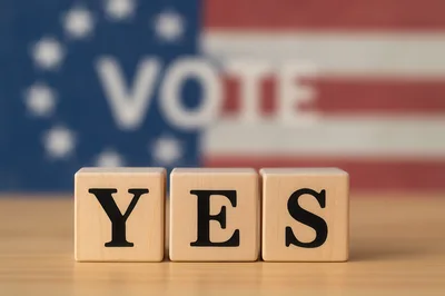 Wooden Blocks Spelling Yes With Blurred American Flag Background