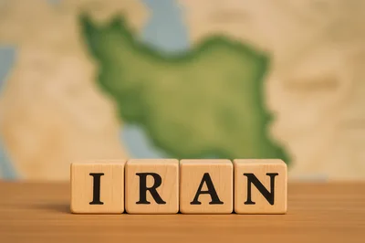 Wooden Blocks Spelling Iran In Front Of A Map