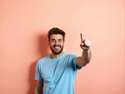 Smiling Man Pointing Upwards Against Peach Background