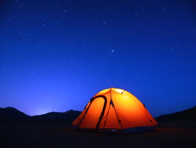Illuminated Orange Camping Tent Under Starry Night Sky