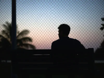 Silhouette of a Man Sitting on a Park Bench