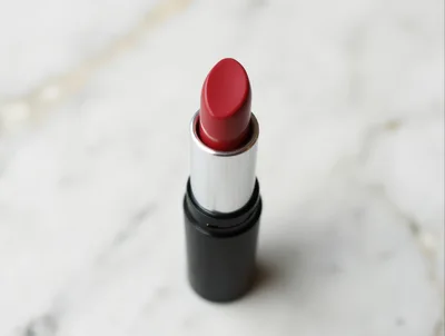 Red Lipstick Tube Standing On White Marble Surface