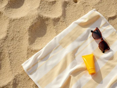 Sunglasses And Sunscreen On A Striped Beach Towel
