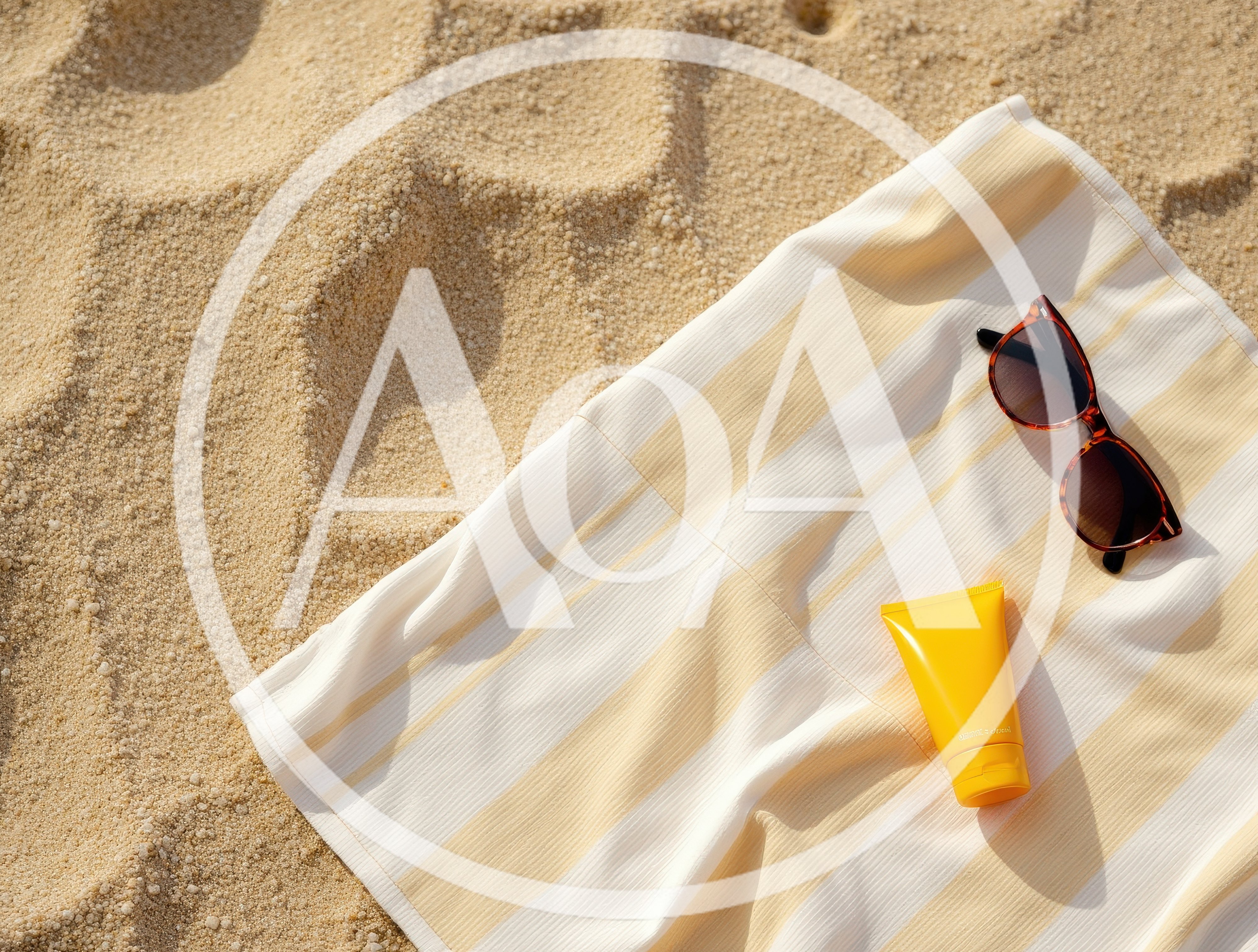 Sunglasses And Sunscreen On A Striped Beach Towel