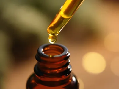 Dropper Dispensing Golden Essential Oil Into Amber Bottle