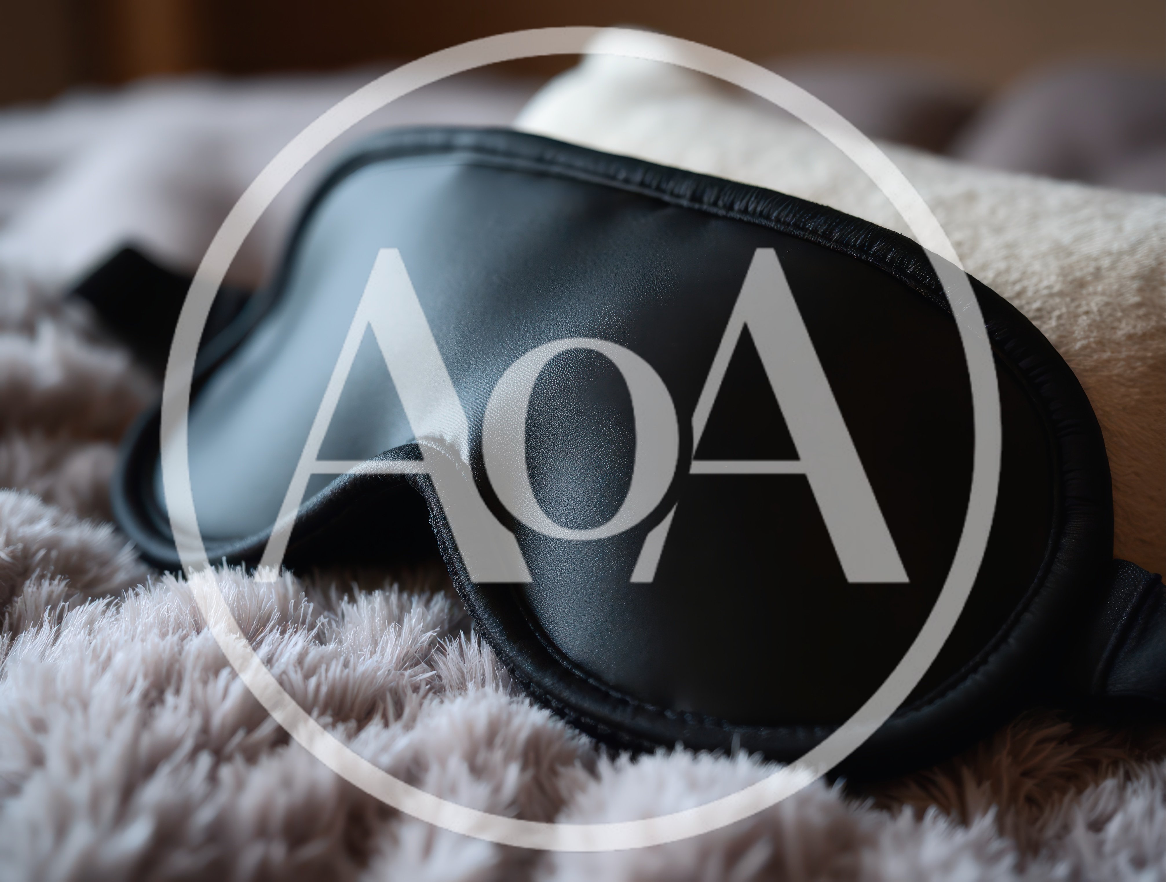 Black Silk Sleep Mask Resting On Soft Blanket