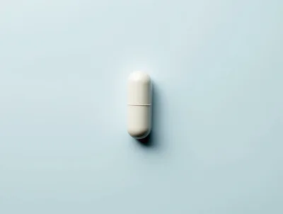 Single White Medical Capsule On Light Blue Background