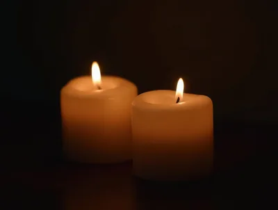 Two Lit Pillar Candles Glowing In The Dark