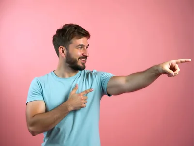 Young Man Pointing To The Side With A Smile