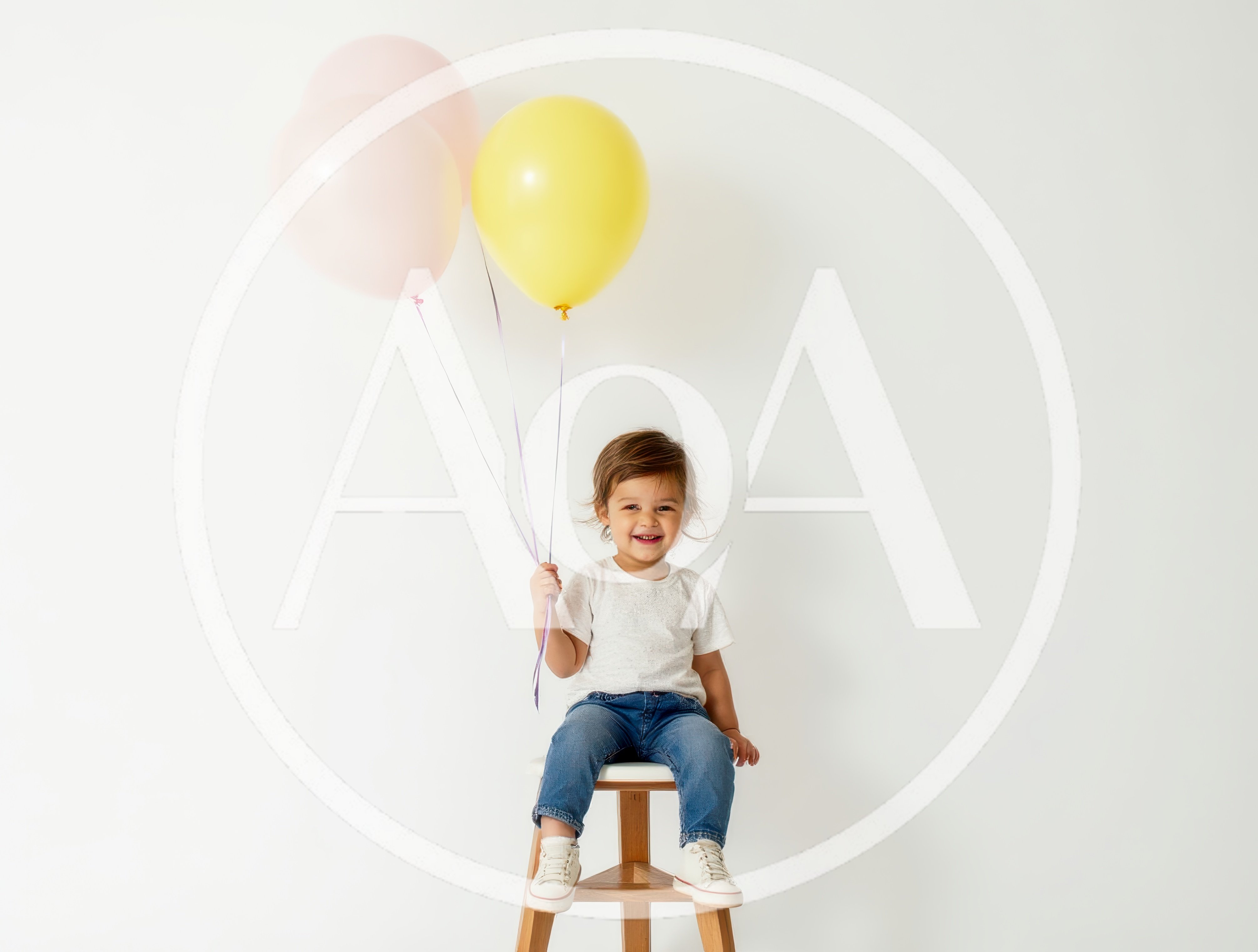 Happy Toddler Sitting on Stool Holding Balloons