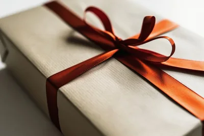 Gift Box Wrapped In Beige Paper With Red Ribbon