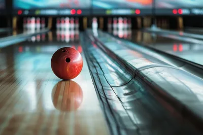 Red Bowling Ball Resting on a Polished Wooden Lane