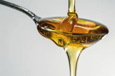 Golden Honey Pouring Over A Metal Spoon