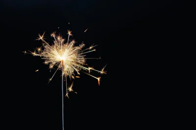 Bright Burning Sparkler Against A Solid Black Background