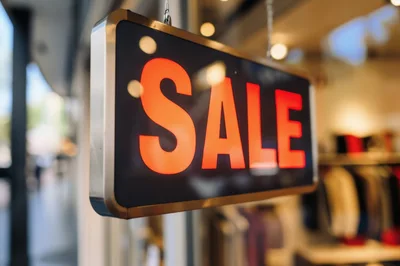 Illuminated Sale Sign Hanging In A Store Window