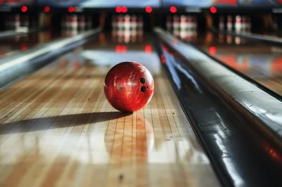 Red Bowling Ball Rolling Down A Wooden Lane