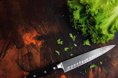 Chef Knife and Fresh Lettuce on Dark Textured Surface