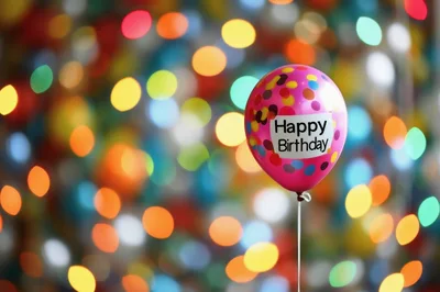 Pink Happy Birthday Balloon Against Colorful Bokeh Lights
