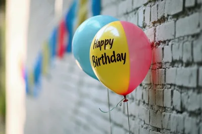 Happy Birthday Balloon Against A White Brick Wall