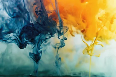 Blue and Yellow Ink Droplets Swirling in Water