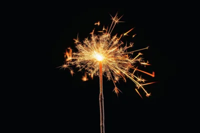 Bright Burning Sparkler Against A Solid Black Background
