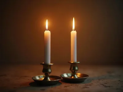 Two Lit White Candles In Brass Holders