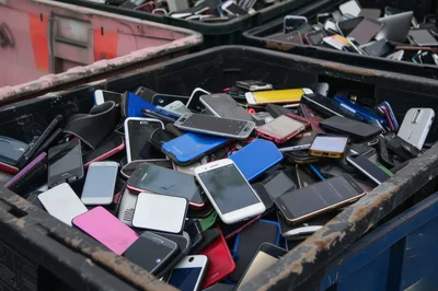 Pile Of Discarded Used Smartphones In Recycling Bin