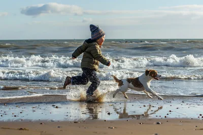 Young Boy Running With Dog On Beach