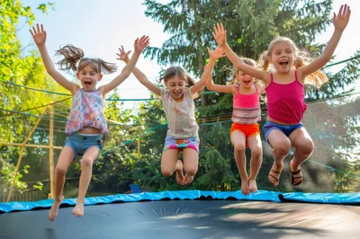 Four Happy Young Girls Jumping Together On A Trampoline