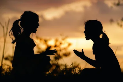 Silhouetted Young Girls Talking Outdoors At Sunset