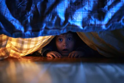 Scared Child Hiding Under Bed Covers