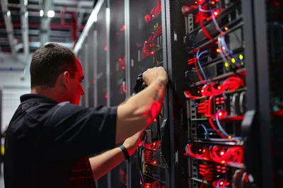 IT Technician Working On Server Rack In Data Center