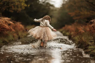 A little girl jumps into a puddle in her beautiful dress and wel