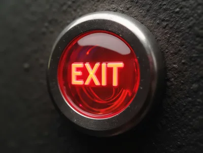 Illuminated Red Exit Push Button On Dark Wall