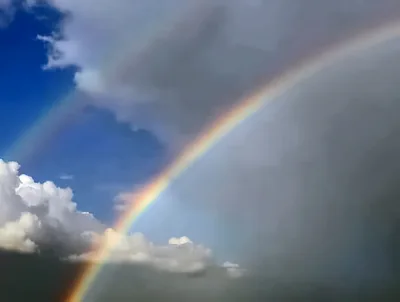 Double Rainbow Arching Across A Cloudy Blue Sky