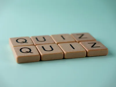 Wooden Scrabble Tiles Spelling Quiz On Teal Background