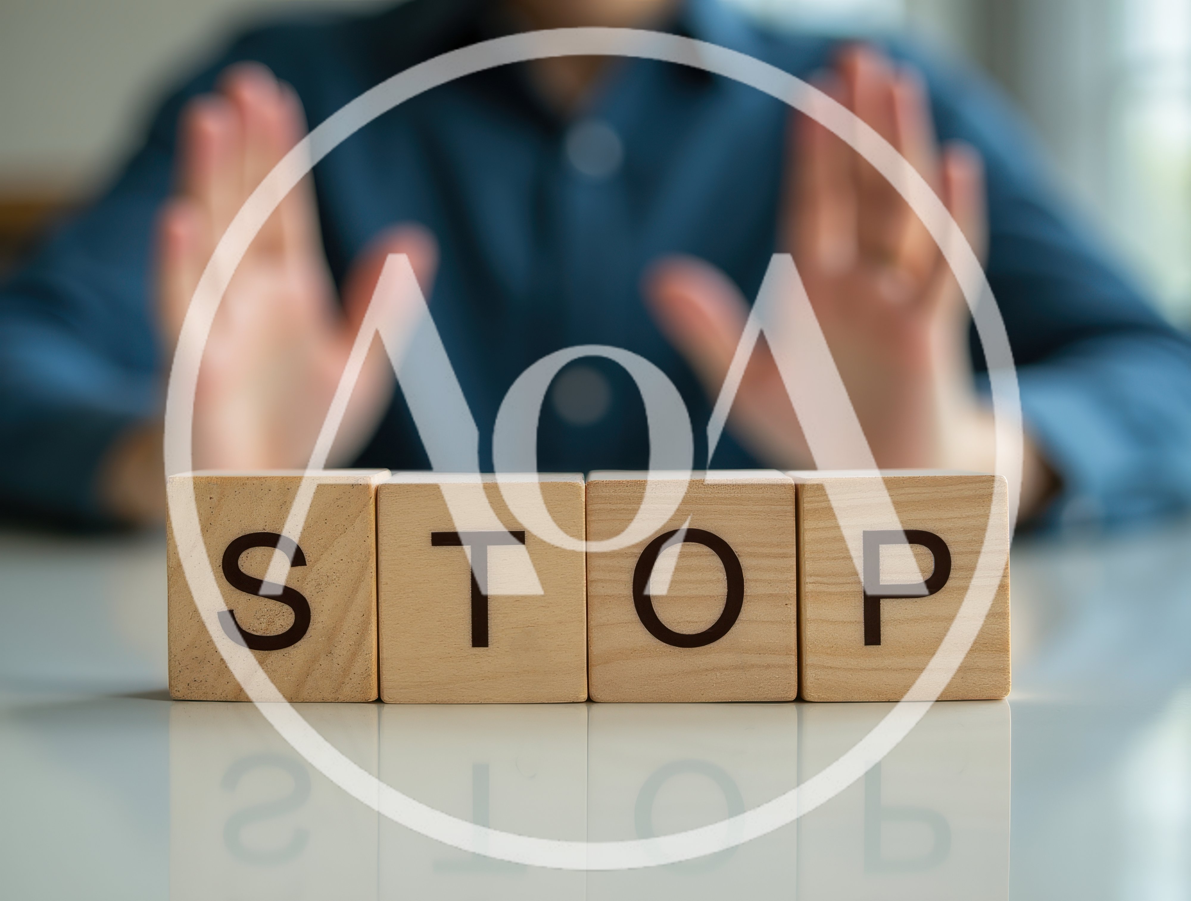 Person Making Stop Gesture Behind Wooden Blocks
