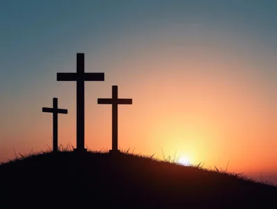 Three Christian Crosses Silhouetted Against A Sunset Sky