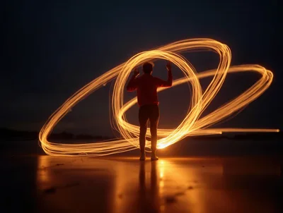 Person Creating Light Painting Orbs On Beach At Night