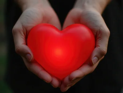 Person Holding A Glowing Red Heart Shape