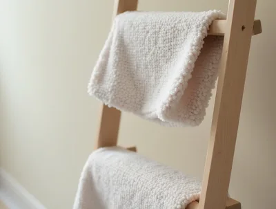 White Textured Blankets Hanging On Wooden Ladder