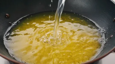Pouring Clear Liquid Into Hot Cooking Oil