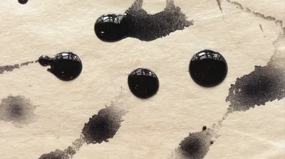 Black Ink Droplets On Textured Paper Background