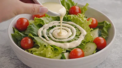 Creamy Dressing Being Poured Over Fresh Garden Salad